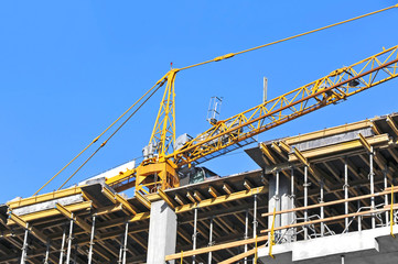 Crane and building construction site against blue sky