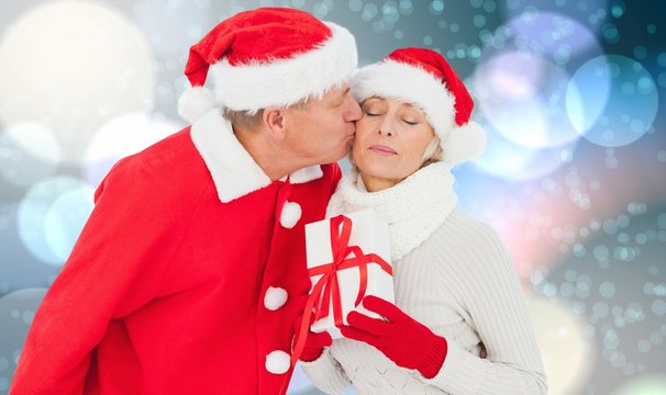 Composite image of festive mature couple holding gift