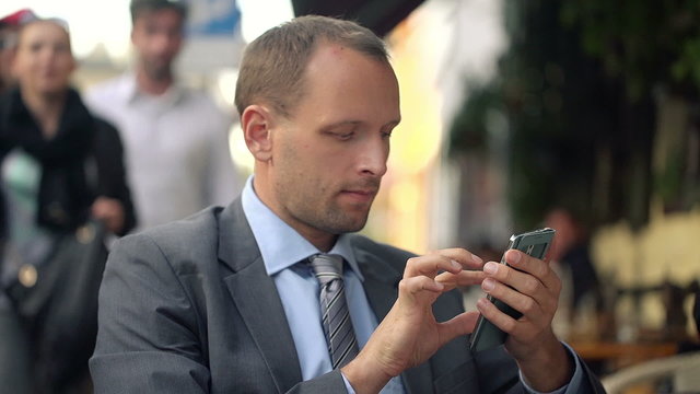 Businessman texting, sending sms on smartphone in cafe