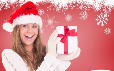Composite image of festive blonde holding a gift