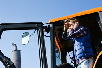Naklejka premium cheerful young woman farmer driving tractor in the fields