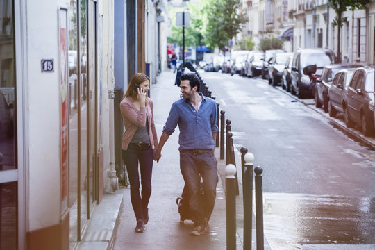 France, Paris, couple on the move with rolling suitcase