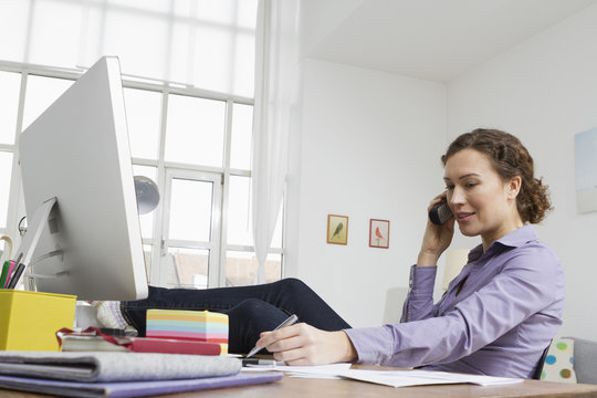 Woman at home at desk with computer and telephone