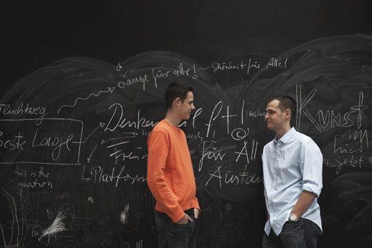 Germany, Berlin, Two men standing against blackboard