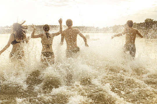 Four friends running into quarry pond