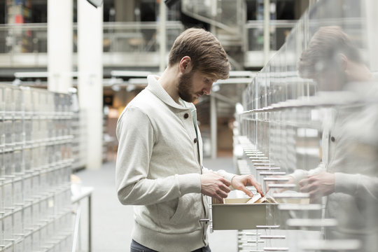 Student in a university library at filing cabinet