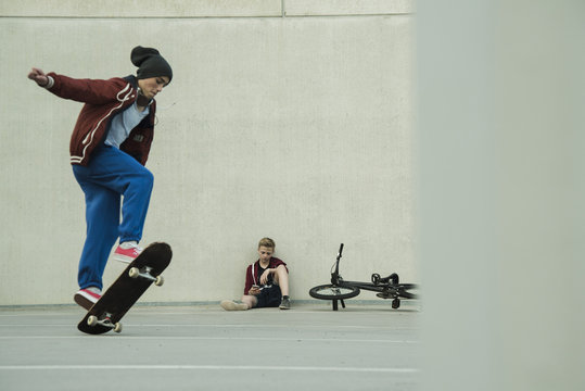Two boys with BMX bike and skateboard on parking level