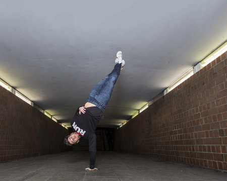 Young breakdancer performing a handstand in underpass
