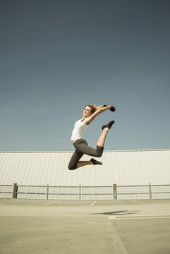 Young woman jumping mid-air on parking level
