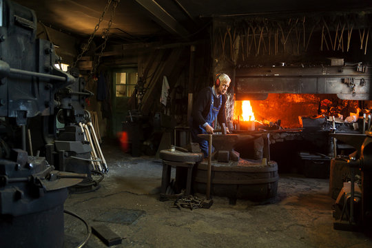 Germany, Bavaria, Josefsthal, senior blacksmith at work in historic blacksmith's shop