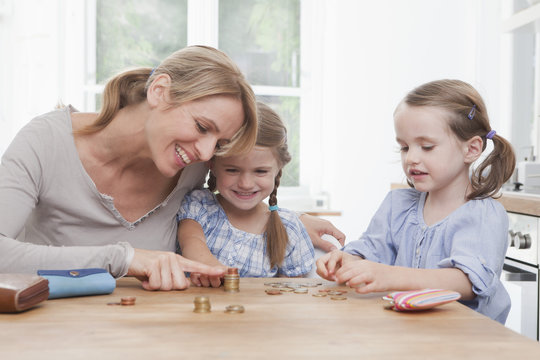 Germany, Munich, Mother with daughters counting stack of coins