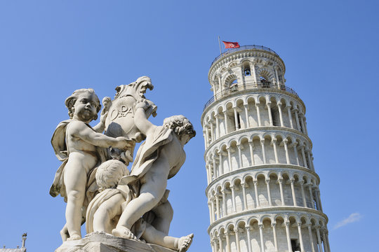 Italy, Tuscany, Pisa, view to Cherub statue and Leaning Tower of Pisa in front of blue sky