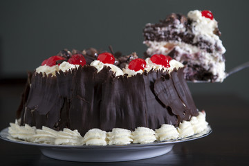 chocolate cake with cream and cherries, being served.