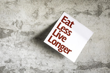 Eat Less Live Longer on Paper Note with texture background