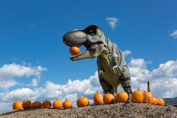 dinosaur holding pumpkin in mouth