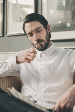 Portrait of young man lightning a cigarillo