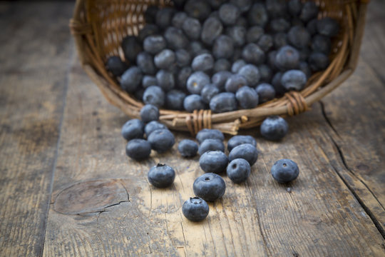 Part of wicker basket with blueberries Vaccinium myrtillus on wooden table
