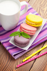 Colorful macaron cookies and cup of milk