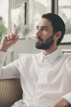 Portrait of young man smoking cigarillo