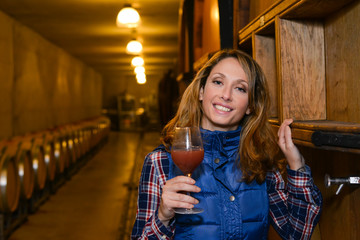 cheerful young woman oenologist tasting wine in cellar