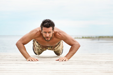 Fit shirtless male fitness model in push up exercise