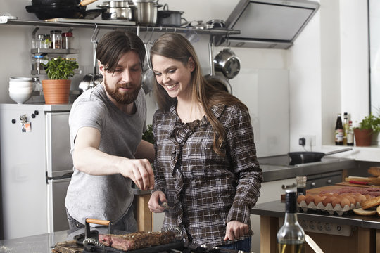 Couple preparing steak in kitchen