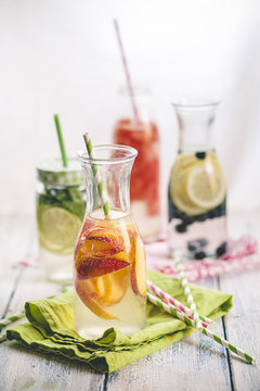 Carafes of miscellaneous fruit infused water on cloth and wood