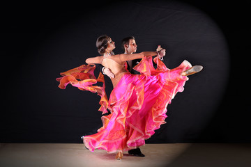 Latino dancers in ballroom against black background