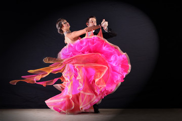 Latino dancers in ballroom against black background