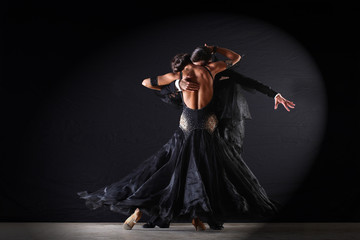 Latino dancers in ballroom against on black background - obrazy, fototapety, plakaty