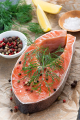 raw salmon steak, lemon, spices prepared for cooking, vertical