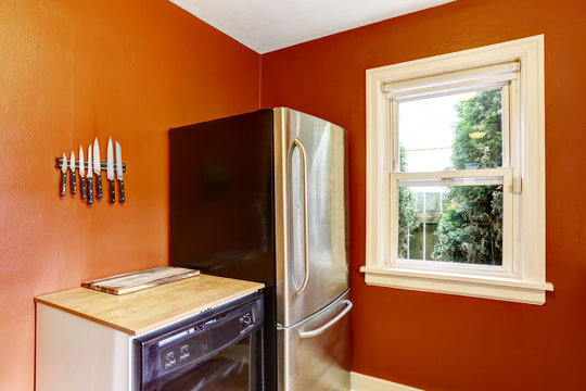 Kitchen corner with bright red walls and steel refrigerator