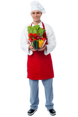 Chef holding glass bowl full of vegetables
