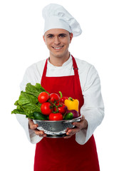 Smiling male chef with fresh vegetables