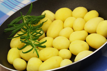 Baby potatoes with fresh rosemary in frying pan, close up