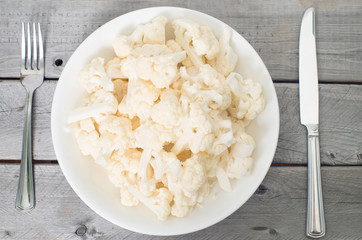 Vegetarian concept with a big plate of raw cauliflower and a kni