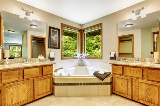 Luxury bathroom interior with two vanity cabinets and corner bat