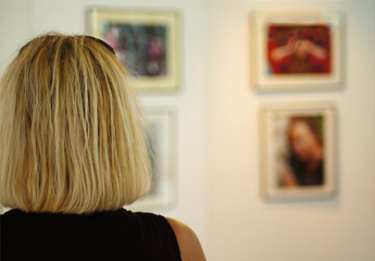 Blonde Frau betrachtet Bilder einer Ausstellung