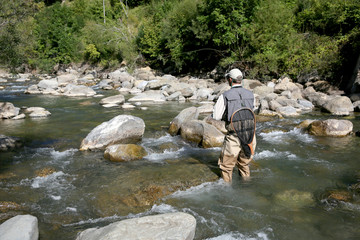 Back view of fly fisherman fishing in river