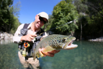 Fly fisherman holding fario trout recently caught