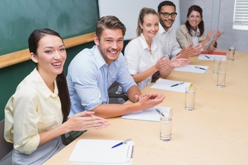 Business team sitting in a row clapping at camera