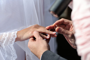 Obraz na płótnie Canvas Groom putting ring on bride's finger