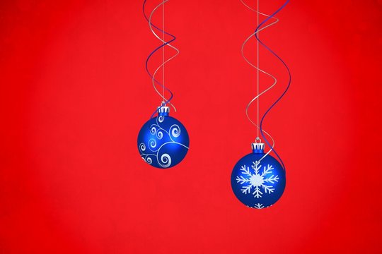 Composite image of two hanging blue bauble decorations
