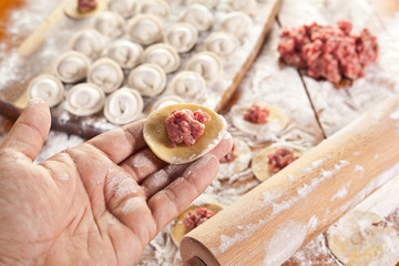 Dumplings. Dough with meat filling on the cook's hands.