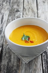 Pumpkin soup in a ceramic plate on a wooden background