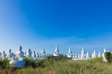 raw of white buddha status on blue sky background