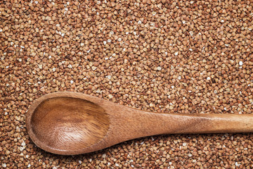 buckwheat background with brown wooden spoon