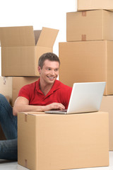 Smiling young man with laptop on box.