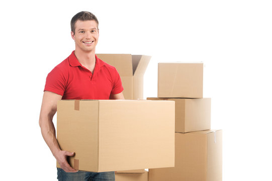 man holding moving box and smiling at camera.