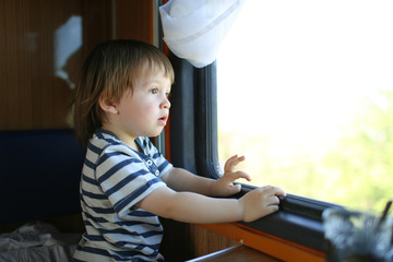 toddler boy looking out of window in the train